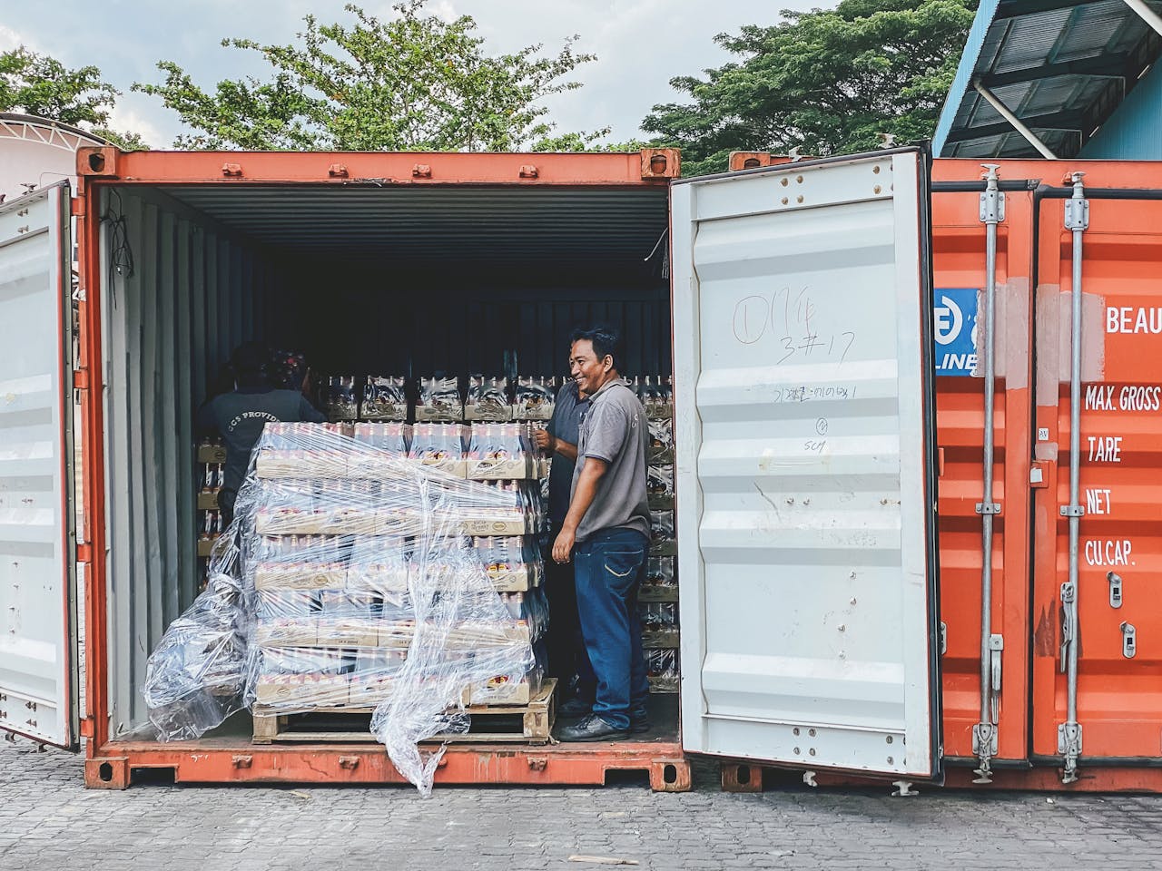 get-in-touch Two men load products into a shipping container in Ipoh, Malaysia, showcasing logistics.
