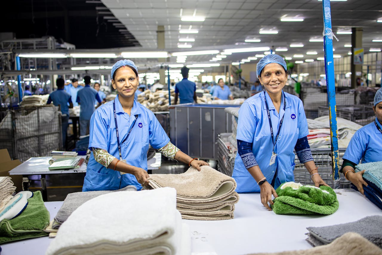 Two female workers in a textile factory sorting and organizing towels on a production line.