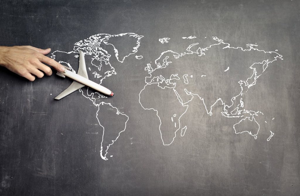 pexels photo 3769146 From above of crop anonymous person driving toy airplane on empty world map drawn on blackboard representing travel concept