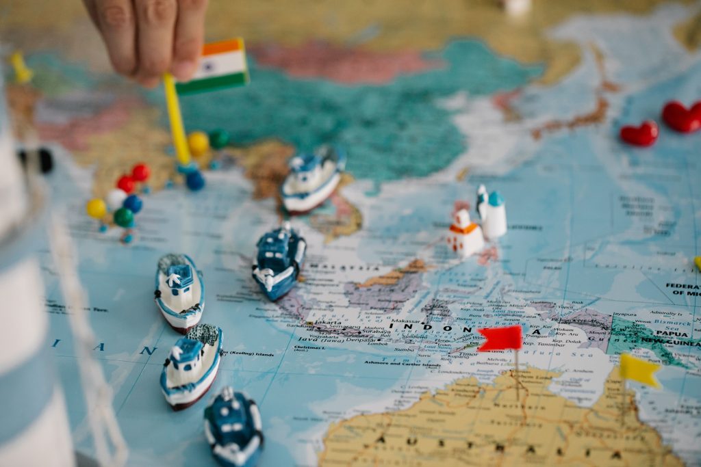 pexels photo 8828390 8828390 A detailed view of a world map with tiny model ships and flags indicating locations, highlighting global trade routes.
